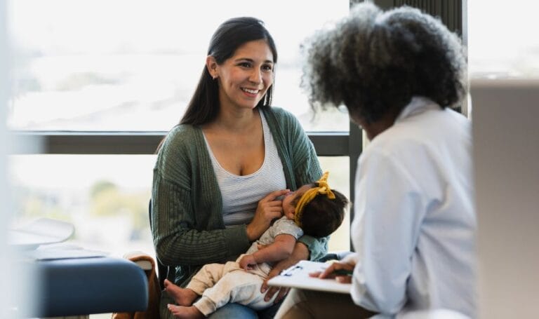 Cheerful mother holding her baby girl in doctors appointment